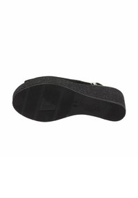 Semelle de chaussure plateforme noire avec surface en caoutchouc texturé, présentant des rainures horizontales, un logo en triangle et des accents scintillants pour une adhérence et un soutien.