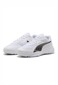 Chaussures de sport blanches en mesh et matière synthétique, avec un motif noir incurvé et une semelle texturée pour une meilleure adhérence. Design avec lacets.