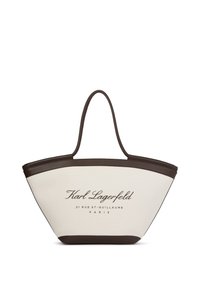 Kangaskassi, jossa on kerma-valkoinen karkea pinta ja ruskea synteettinen reunus, varustettuna kahdella olkahihnalla ja tummanruskealla painettulla brändiloggolla.