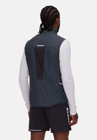 Mammut ärmlös väst i mörkgrått med svarta accenter, mjukt, lättviktigt material och reflexdetaljer. Funktioner logotplats på ryggen.