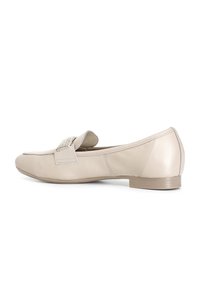 Beige leren platte loafers met een lage hak en een met strass versierde band over de bovenkant, weergegeven in zijaanzicht op een witte achtergrond.