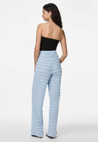 Lichtblauwe, gestructureerde high-waisted broek met horizontale strepen. Kenmerkt zich door een cinched tailleband, een wijd beenontwerp en een gladde afwerking.