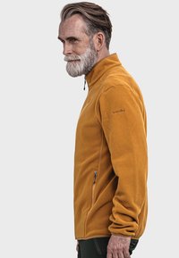 Fleece-Jacke in Senfgelb, mit einem Reißverschlusskragen und seitlichen Taschen. Sie hat eine glatte Textur und eine lockere Passform, die für Komfort sorgt.