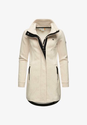 Ljusbeige jacka med hög krage, svart dragkedja och två sidofickor med dragkedja. Har ett texturerat tyg och kontrasterande svarta detaljer.