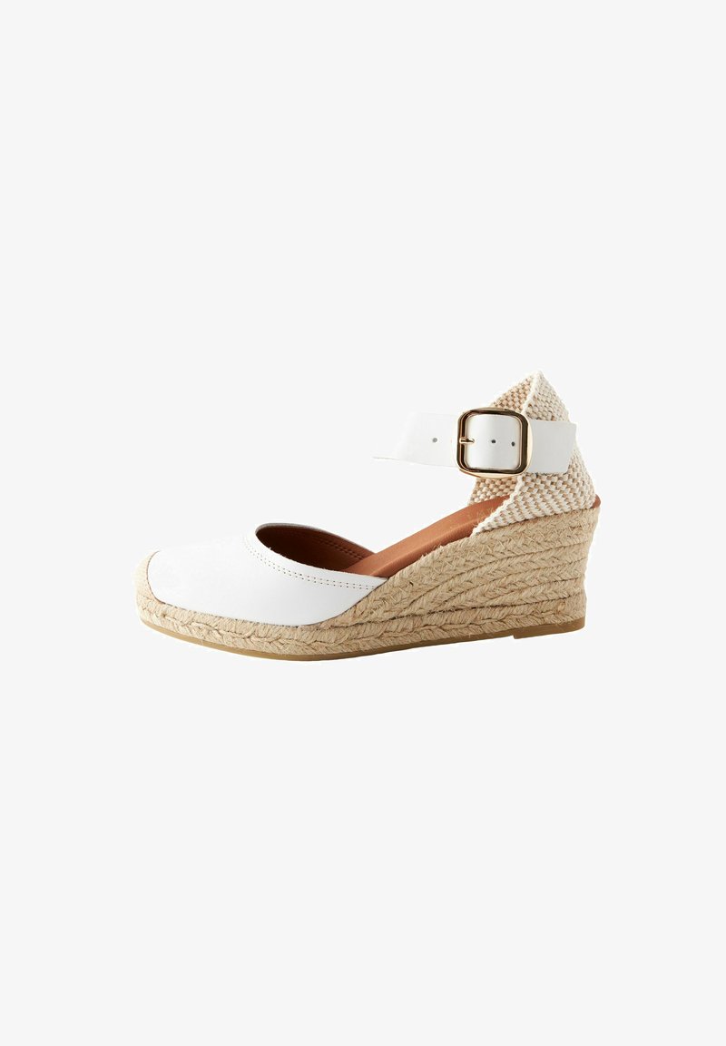 White wedge shoe with a closed toe, featuring a textured jute-covered heel and an ankle strap with a gold buckle accent.