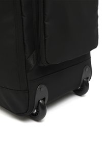 Black soft fabric suitcase corner showing dual black wheels and bottom zipper pocket on white background.