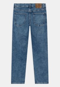 Blue denim jeans shown from the back, featuring two patch pockets and a brown leather brand label on the waistband.