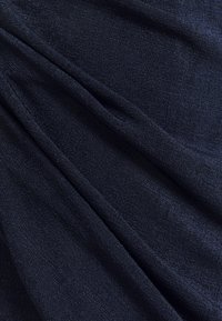 Tessuto blu scuro con una finitura morbida e testurizzata, caratterizzato da una leggera lucentezza e un motivo a coste verticali, drappeggiato in modo fluido.