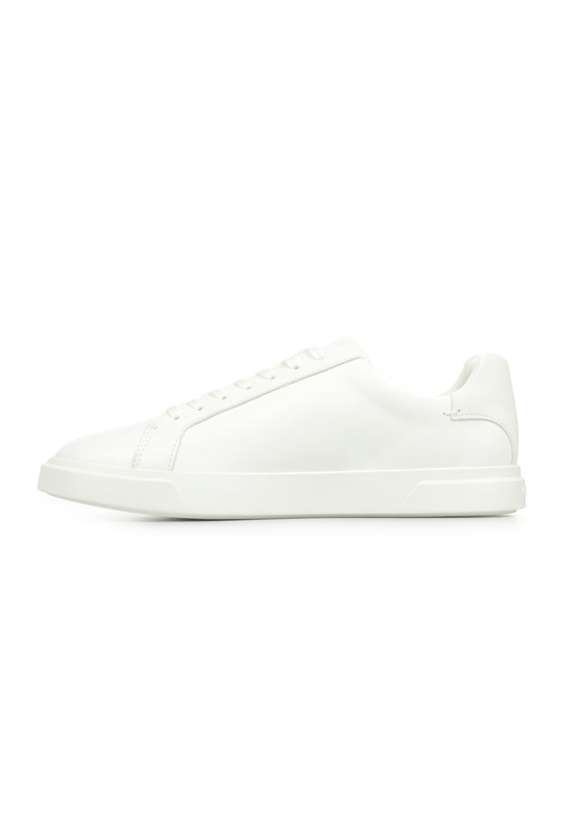 Białe skórzane sneakersy mają gładką powierzchnię, niski profil, okrągły czubek oraz sześć oczek do sznurowania. Minimalistyczny styl.