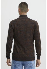 Strikket genser med en teksturert blanding av mørkeblå og oransje, med høy krage og ribbede mansjetter og nederkant.