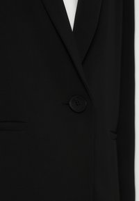 Zwarte blazer met een gladde textuur, voorzien van een enkele knoopsluiting, geremde revers en zijzakken.