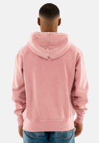 Sudadera de algodón rosa con un corte relajado, puños y dobladillo acanalados, que presenta una capucha grande con cordón y una apariencia suave y texturizada.