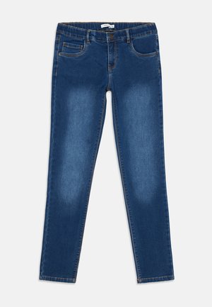 Jeans azul de corte ajustado con bolsillos frontales, presillas para cinturón, cierre de botón y un leve desgaste en los muslos, dispuestos sobre un fondo blanco.