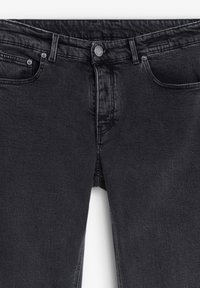 Jeans de mezclilla negros con un diseño clásico, cierre de cremallera, dos bolsillos delanteros y un ligero desgastado. Textura suave con costuras mínimas.