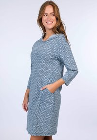 Helles blaues Kleid mit Kapuze, das ein geometrisches Muster aufweist, Dreiviertelärmel hat und Seitentaschen besitzt. Hergestellt aus weichem, strukturiertem Stoff.