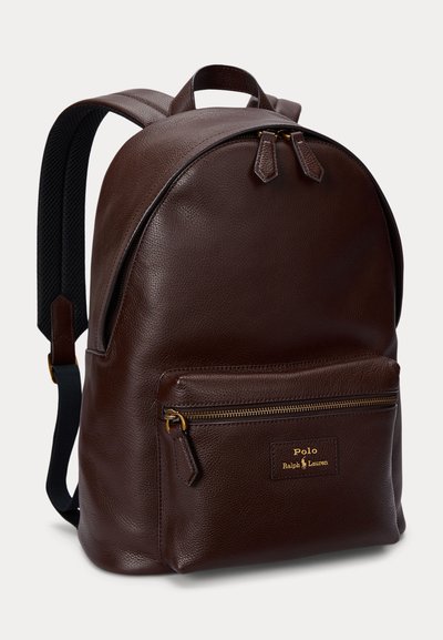 Sac à dos en cuir marron foncé avec poche avant zippée, fermeture éclair dorée, bretelles noires réglables, et patch logo Polo Ralph Lauren.