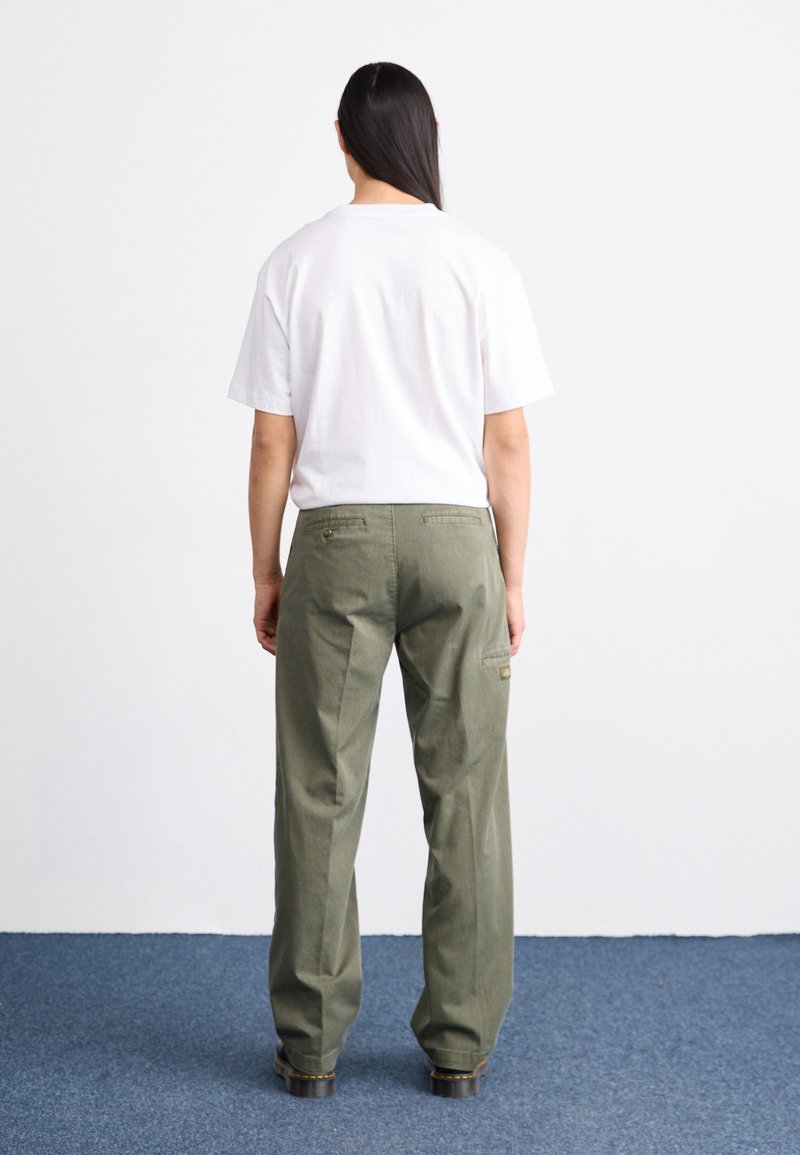 Olivgrüne Cargo-Hosen mit einem lockeren Schnitt, ausgestattet mit Gesäßtaschen und einer seitlichen Tasche. Kombiniert mit einem schlichten weißen T-Shirt mit Rundhalsausschnitt.