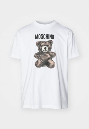 Valkoinen puuvillapaita, jossa musta graafinen kuva karhusta ja teksti "MOSCHINO" ylhäällä. Pyöreä kaula-aukko ja rento malli.