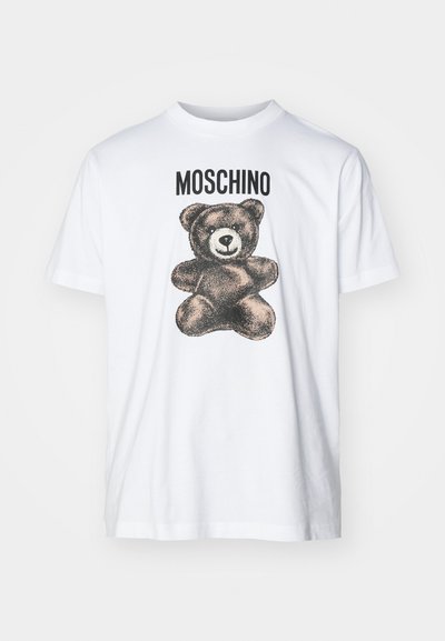 Camiseta de algodón blanca con un gráfico negro de un oso y el texto "MOSCHINO" arriba. Cuello redondo y corte relajado.