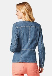 Jeansjacke mit taillierter Passform, in mittelblauer Farbe und sichtbaren Nahtdetails. Verfügt über lange Ärmel und einen runden Ausschnitt.