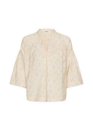 Blouse jaune pâle à manches trois-quarts bouffantes, ornée d'un motif floral bleu. Encolure en V et détails froncés aux épaules.
