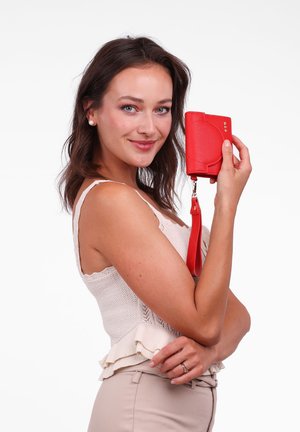 Red wallet made of textured material, featuring a rounded design, wrist strap, and subtle hardware accents.