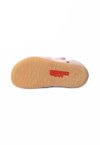 Różowa podeszwa buta sportowego z teksturowanej gumy, charakteryzująca się rowkowanym wzorem i czerwonym logo. Miękka różowa cholewka o prostym wzorze z rzepem.