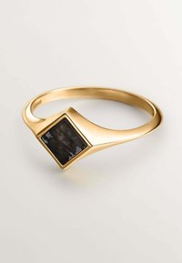 Anillo de oro con una piedra negra cuadrada engastada en ángulo, con una banda lisa y curvada y acabado pulido.