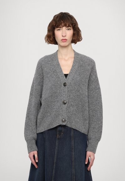 Cardigan en tricot gris avec un col en V, cinq grands boutons noirs et des manches larges. Le tissu a une apparence texturée et côtelée.