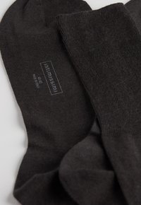 Dunkelgraue Baumwollsocken mit einer glatten Textur, die ein dezentes Logo und Größenetikett an der Seite aufweisen. Enthalten eine nahtlose Zehenpartie für zusätzlichen Komfort.