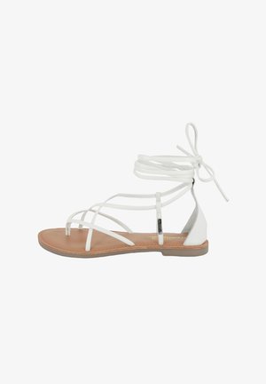 Witte sandalen met bandjes met een platte zool, leren straps en enkelschoenen. De zool is tan met een gladde textuur en minimale versieringen.