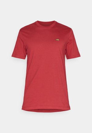 T-shirt en coton rouge à manches courtes et col rond. Présente un petit logo vert sur la poitrine. Texture lisse, coupe classique.