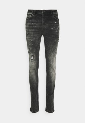 Jean en denim noir avec une finition délavée, présentant des zones usées et de légères éclaboussures de peinture. Coupe slim avec une conception à jambes droites.