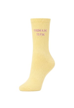 Gelber Crew-Socken mit gerippter Struktur und pinkem Text mit der Aufschrift "FROM A.M. TO P.M." nahe dem oberen Bündchen.