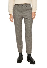Pantalons en motif pied-de-coq noir et blanc avec une coupe ajustée, jambes droites et poches avant, associés à des bottines noires.
