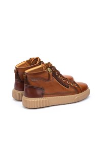 Baskets montantes en cuir marron avec des semelles en caoutchouc beige contrastantes, laçage à l'avant et fermeture éclair sur le côté extérieur. Accents texturés.