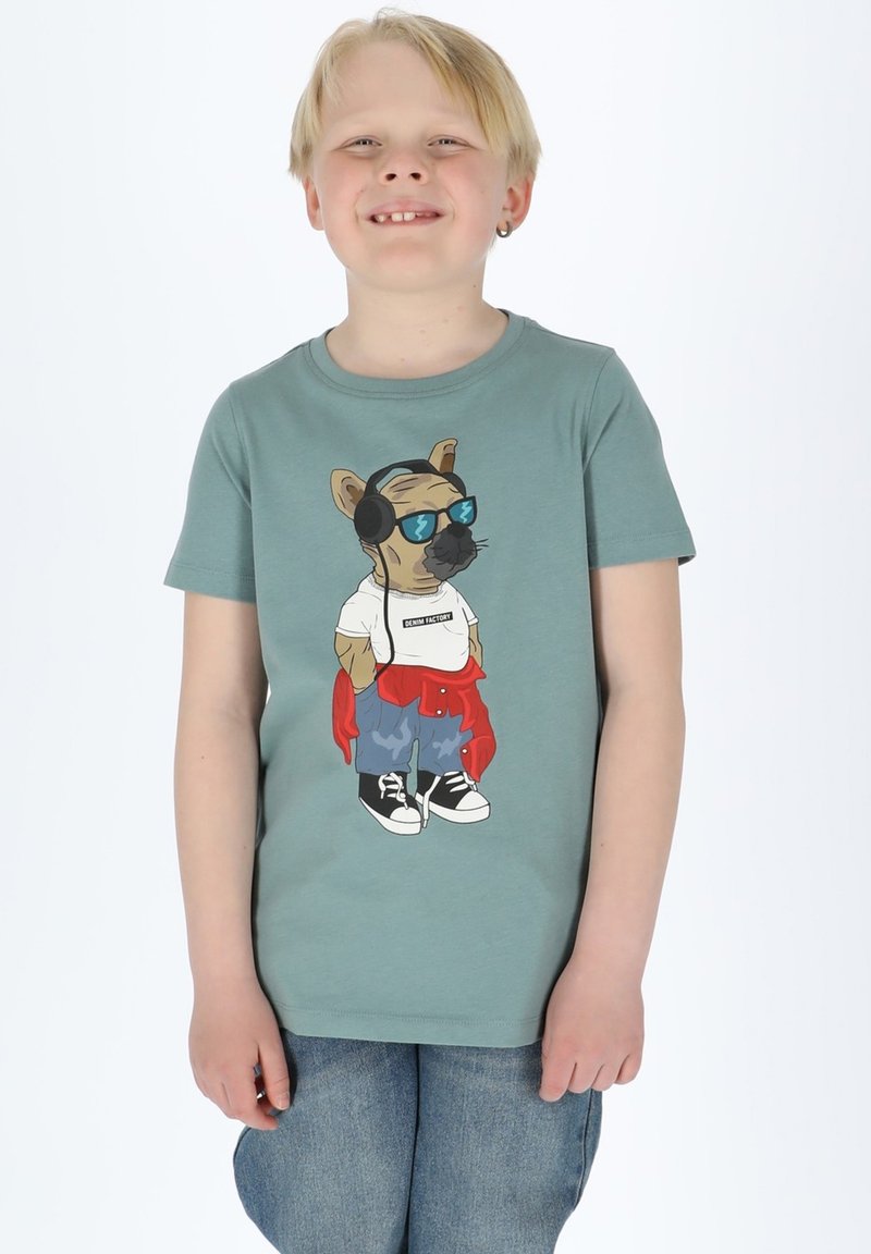 Grön t-shirt med kort ärm som har en tecknad hund med glasögon och hörlurar, bära en vit skjorta, röd hoodie och blå jeans.