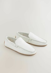 Biele kožené slip-on topánky s textúrovaným povrchom, zaoblenou špičkou a viditeľným prešívaním. Majú hnedú gumovú podrážku a minimalistický dizajn.