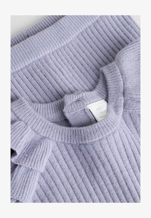 Šviesiai purpurinė pylimo tekstūros megztinis su raukiniais kairėje petyje. Turi apvalų iškirpimą ir etiketę su prekės ženklu bei priežiūros instrukcijomis.
