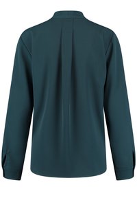 Camicia a maniche lunghe di un blu scuro con colletto e dettaglio delle pieghe sul retro. Tessuto liscio e polsini con bottoni. Vestibilità su misura con orlo curvo.