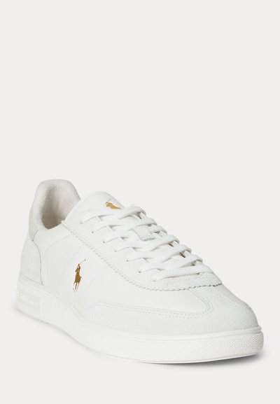 Fehér bőr sneaker velúr részletekkel, fehér fűzővel és arany Polo Ralph Lauren logóval az oldalon és a nyelvnél, enyhe szögben bemutatva.