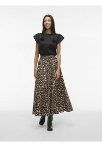 Maglietta nera con accenti ricamati sulle spalle, abbinata a una lunga gonna leopardata. La modella indossa stivali neri alla caviglia.