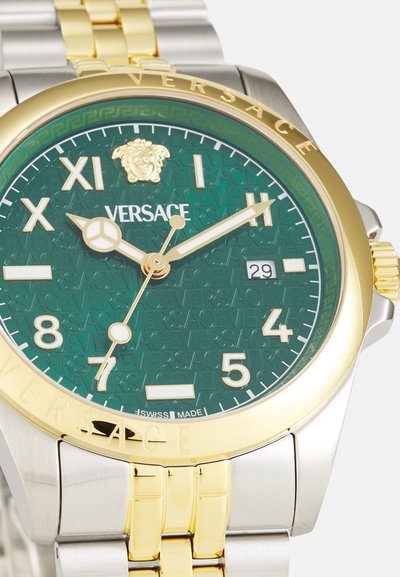 Montre Versace avec un cadran à motif vert, un boîtier en acier inoxydable doré et argenté, des accents dorés et un affichage de la date à 3 heures.