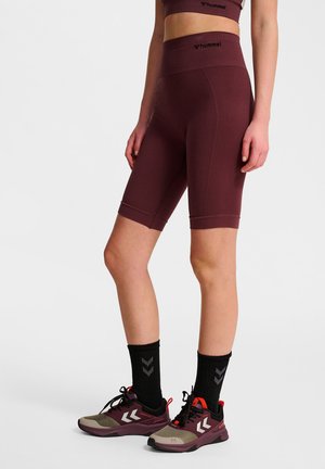 Bordeaux wielershorts in een gestructureerde stof, met een hoge taille, gecombineerd met zwarte crew-sokken en bordeaux sportieve schoenen.