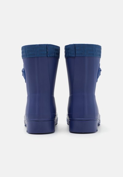 Bottes en caoutchouc de marine avec des poignets en textile à motifs, texture lisse et bouts arrondis, conçues pour un usage imperméable.