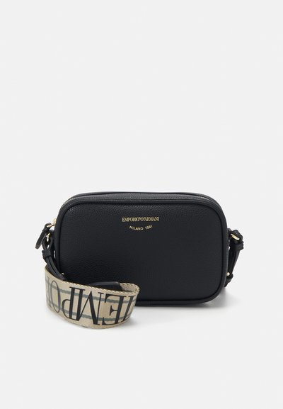 Schwarze Leder-Crossbody-Tasche mit goldenem Logo, Reißverschluss und einem gemusterten Stoffgurt mit kontrastierendem Text. Rechteckige Form, strukturierte Oberfläche.