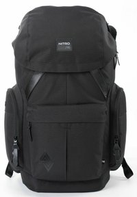 Schwarzer Stoff-Rucksack mit einer oberen Klappe, verstellbaren Trägern, mehreren Reißverschlussfächern und einem strukturierten Logo-Detail auf der Vorderseite.