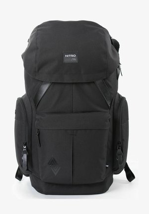 Zaino in tessuto nero con pattina superiore, spallacci regolabili, molteplici scomparti con zip e un dettaglio del logo testurizzato sul fronte.