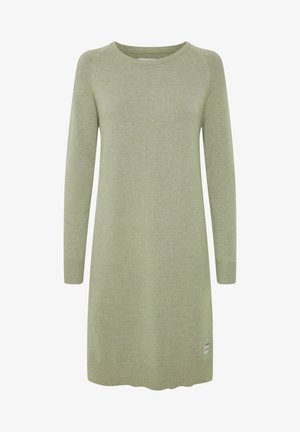 Világoszöld kötött ruha hosszú ujjakkal, kerek nyakkal és bordázott mandzsettákkal. Felső részén egy logócímke található az aljánál, és enyhén ívelt alsó széle van.