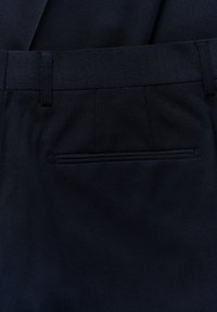 Mörkblå byxor i texturerat tyg med slät framdel, bältesloopar och en bakficka med dold dragkedja.